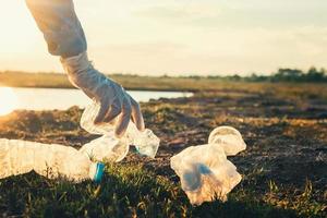 main de femme ramassant une bouteille en plastique à ordures pour le nettoyage au parc photo