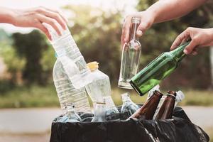 les gens tiennent une bouteille d'ordures en plastique et en verre dans un sac de recyclage pour le nettoyage photo