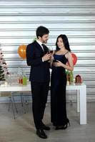 doux couple aime sourire et passer du romantique en buvant du vin à noël et en célébrant le nouvel an, la saint valentin avec des ballons colorés et des coffrets cadeaux au garde-manger photo