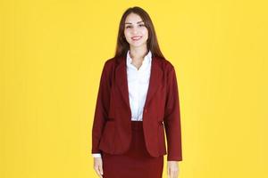 femme d'affaires caucasienne en costume rouge souriante et intelligente isolée sur fond jaune. photo
