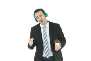 homme d'affaires beau et intelligent se détendre en écoutant de la musique dans des écouteurs verts et main tenant une tasse de café isolé sur fond blanc. concept d'entreprise et de finance. copie espace photo