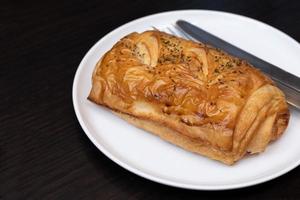 tarte feuilletée au jambon et au fromage, servie sur une assiette ronde en céramique blanche. mise au point sélective photo