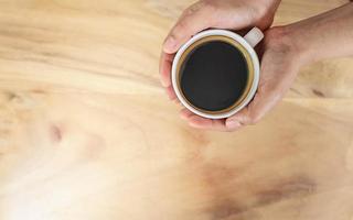 tasse à café noire à la main sur une table en bois. photo