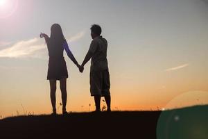 silhouette d'un homme et d'une femme se tenant la main, marchant ensemble. photo