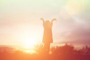 silhouette d'enfant, moments de joie de l'enfant. sur le coucher de soleil nature photo