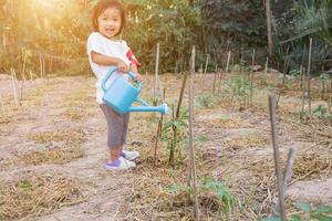 petite fille arrosant un arbre avec un arrosoir photo