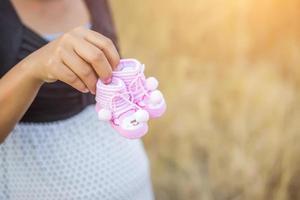 femme enceinte tenant des chaussures de bébé photo