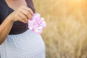 femme enceinte tenant des chaussures de bébé photo