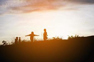 silhouette d'enfants heureux et coucher de soleil heureux photo