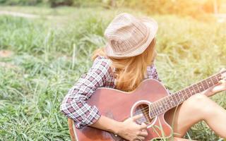 jeune fille hipster assise jouant de la guitare et chantant. photo