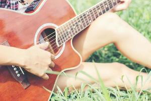 jeune fille hipster assise jouant de la guitare et chantant. photo