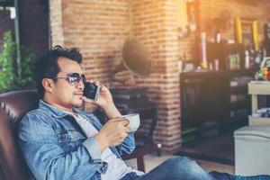 jeune homme avec smartphone souriant relaxant au café. photo