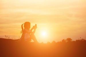 silhouette d'enfant, moments de joie de l'enfant. sur le coucher de soleil nature photo