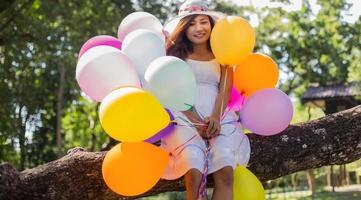 jeune adolescente assise sur un arbre et tenant des ballons à la main photo