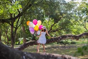 jeune adolescente assise sur un arbre et tenant des ballons à la main photo