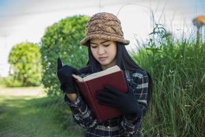 hipster charmante fille se détendre dans le parc tout en lisant un livre, profiter de la nature autour. photo