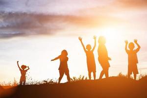 silhouette d'enfants heureux et coucher de soleil heureux photo