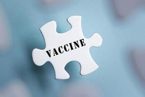 mot de vaccin sur des pièces de puzzle isolées sur fond bleu flou. photo