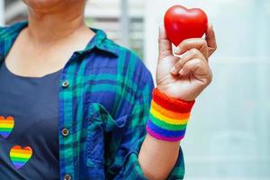 femme asiatique tenant un hert rouge avec un drapeau arc en ciel, droits des symboles lgbt et égalité des sexes, mois de la fierté lgbt en juin, lgbtq, lgbti, lgbtqa, lgbtqia photo