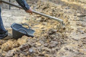 le jardinier creuse le sol avec son équipement de jardinage et prépare la terre pour la plantation. photo