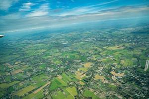 la vue sur le champ vert et la ferme et la ville du centre-ville au milieu de la thaïlande. il a tiré d'un avion à réaction. photo