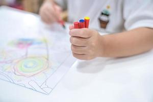 petite fille joue et apprend à colorier le crayon sur le papier dans le restaurant de crème glacée., bangkok, thaïlande. photo