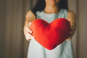 gros plan d'une femme tenant un modèle d'oreiller cardiaque pour la saint valentin, la fête des mères et le mois de sensibilisation au cancer du sein pour les soins de santé de la journée internationale de la femme photo