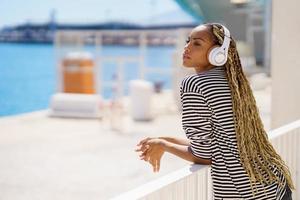 jeune femme noire écoutant de la musique tout en profitant de la vue sur le port maritime. photo