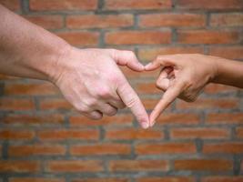 gros plan de faire en forme de coeur avec les mains entre l'homme et la femme avec fond de mur de briques photo