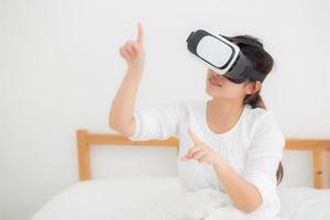 belle jeune femme asiatique joyeuse et amusante portant un casque de réalité virtuelle vr, un appareil pour fille et regardant des divertissements de jeux de simulation à l'avenir, une femme recherchant avec la technologie numérique. photo