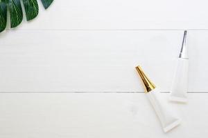 produit cosmétique et de soin de la peau et feuilles vertes sur une table en bois blanc, beauté avec crème de traitement et hydratant sur un bureau en bois, concept de santé et de bien-être, vue de dessus. photo