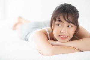 beau portrait jeune femme asiatique allongée et souriante au réveil avec le lever du soleil le matin, beauté jolie fille heureuse et joyeuse reposant sur le lit dans la chambre, mode de vie et concept de détente. photo