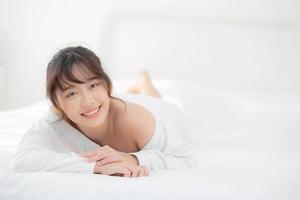 beau portrait jeune femme asiatique allongée et souriante au réveil avec le lever du soleil le matin, beauté jolie fille heureuse et joyeuse reposant sur le lit dans la chambre, mode de vie et concept de détente.