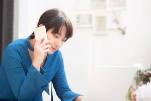 belle jeune femme d'affaires asiatique excitée et heureuse de réussir à travailler avec un ordinateur portable, une fille prenant un téléphone intelligent mobile et un café de travail, concept d'entreprise indépendante de carrière. photo