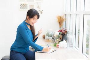 beau portrait femme asiatique écrivain excité d'écrire sur un cahier ou un journal avec plaisir avec succès et heureux, mode de vie asie fille est étudiante, plan féminin travaillant, éducation et concept d'entreprise. photo