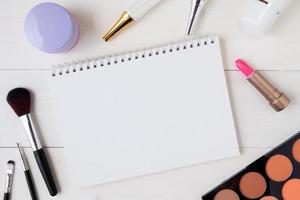 produit cosmétique et de soin de la peau et cahier sur une table en bois blanc, beauté avec crème de traitement et espace de copie hydratant et bloc-notes sur un bureau en bois, concept de santé et de bien-être, vue de dessus. photo