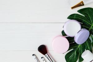 produit cosmétique et de soin de la peau et feuilles vertes sur une table en bois blanc, beauté avec crème de traitement et espace de copie hydratant sur un bureau en bois, concept de santé et de bien-être, vue de dessus. photo