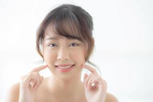 portrait belle femme asiatique maquillage de cosmétique, fille main toucher joue et sourire attrayant, beauté du visage parfaite avec bien-être dans la chambre à la maison avec concept de soins de la peau et de soins de santé. photo