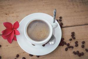 café et bulle dans une tasse à café blanche et une soucoupe avec une cuillère sur fond en bois. photo