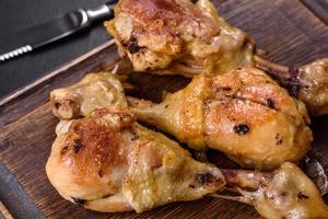 trois cuisses de poulet grillées avec des épices et des herbes sur une planche à découper en bois photo