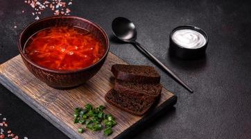bortsch ukrainien traditionnel. bol de bortsch de soupe de racine de betterave rouge à l'oignon vert photo