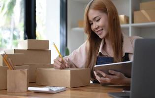 startup réussie propriétaire de petite entreprise PME beauté fille stand avec tablette smartphone dans un café-restaurant. portrait d'une femme asiatique bronzée propriétaire d'un café barista. PME entrepreneur vendeur concept d'entreprise photo