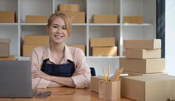 jeune souriant propriétaire de beauté femme asiatique pigiste PME affaires achats en ligne travaillant sur ordinateur portable avec boîte à colis à la maison - PME entreprise en ligne et concept de livraison photo