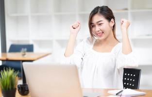 les femmes d'affaires asiatiques sont ravies et satisfaites du travail qu'elles font sur leur ordinateur portable et prennent des notes au bureau. photo