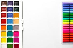 une palette d'aquarelles de couleurs avec des pinceaux et des marqueurs sur un fond blanc avec un espace pour le texte. photo