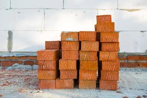 une pile de briques rouges sur un chantier de construction. matériaux de construction, livraison, entrepôt. copie espace photo