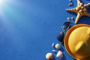 cadre avec accessoires de plage sur un thème nautique chapeau de paille jaune, lunettes de soleil, étoiles de mer et coquillages sur fond bleu. concept de vacances, voyage en mer, protection uv, natation. espace de copie. mise à plat photo