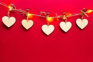 guirlande de coeurs en bois avec des pinces à linge avec l'inscription love sur fond rouge. saint valentin, espace de copie, maquette. lumières de vacances, dépliant, amoureux photo