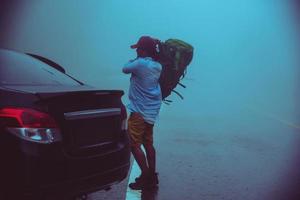 homme asiatique au volant d'une voiture voyageant se détendre la nature. la nature voyageuse au milieu de la brume pluvieuse. pendant la saison des pluies à chiangmai en thaïlande. photo