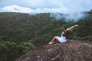 femme asiatique voyage nature. voyager se détendre. liberté voyageur heureux femme debout avec les bras levés et profitant d'une belle nature au sommet de la montagne brumeuse.